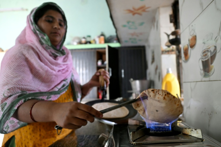 L'agricultrice Gauri Devi cuisine sur un réchaud alimenté par du biogaz issu de bouses de vache, à son domicile dans le district de Bulandshahr, dans l'Uttar Pradesh, le 24 avril 2026 en Inde ( AFP / Arun SANKAR )