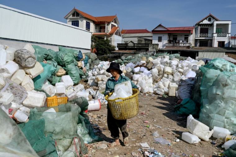 Un homme travaillent dans une décharge de déchets plastiques dans un village situé à la périphérie de Hanoï, le 25 novembre 2025 ( AFP / Nhac NGUYEN )