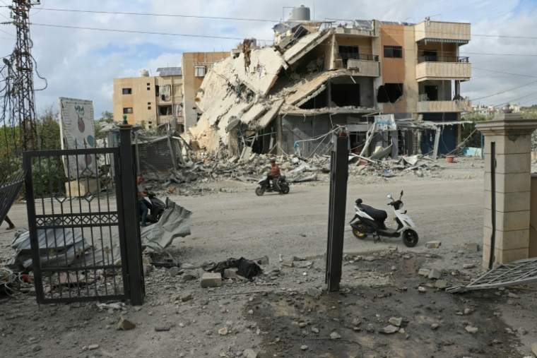 Un homme passe en moto devant un bâtiment abritant une ONG, détruit par une frappe israélienne, dans la ville de Tyr, dans le sud du Liban, le 15 mai 2026 ( AFP / Kawnat HAJU )