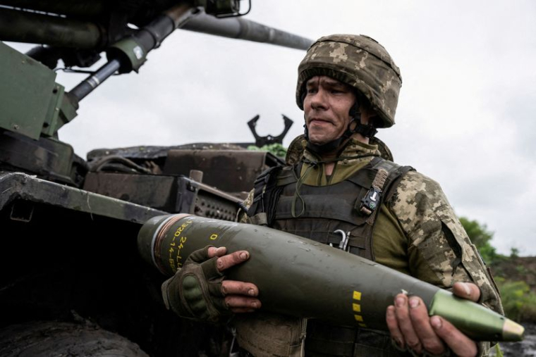 Un militaire ukrainien porte un obus pour un obusier automoteur Caesar avant de tirer en direction des troupes russes près d'Avdiivka