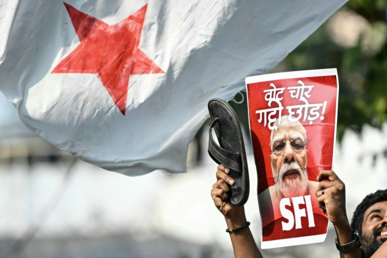 Une étudiante militante brandit une affiche du Premier ministre indien Narendra Modi lors d’une manifestation réclamant la démission du chef de la Commission électorale nationale, Gyanesh Kumar, à New Delhi, le 14 octobre 2026 ( AFP / Arun SANKAR )