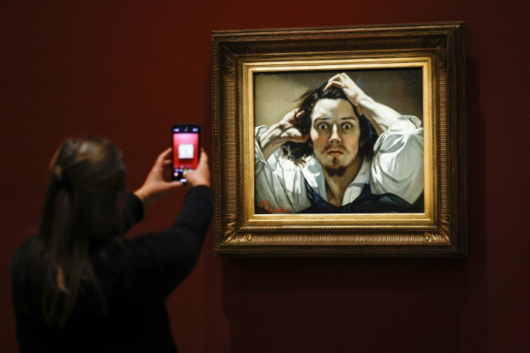 Une personne prend en photo le tableau "Le Désespéré" célèbre autoportrait du peintre français Gustave Courbet, exposé au musée d'Orsay à Paris, le 13 octobre 2025 ( AFP / Ian LANGSDON )