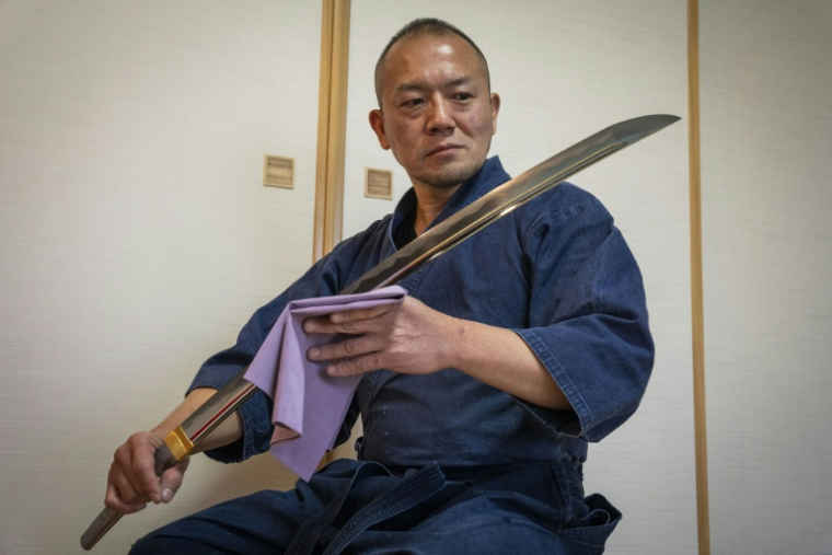 Le forgeron Akihira Kawasaki examine une lame de katana dans son atelier de Misato, dans la préfecture de Saitama, le 9 janvier 2026 au Japon ( AFP / Yuichi YAMAZAKI )