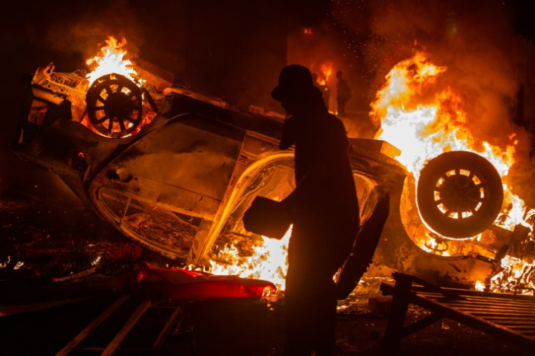 Une voiture est incendiée lors d'une manifestation à Yogyakarta, le 29 août 2025 en Indonésie, après la mort d'un chauffeur de taxi-moto, écrasé par un véhicule des forces de l'ordre ( AFP / Devi RAHMAN )