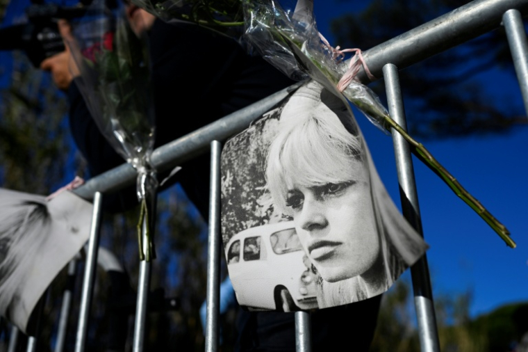 Un portrait et des fleurs accrochés sur une barrière en hommage à Brigitte Bardot à l'entrée de sa propriété de Saint-Tropez, le 28 décembre 2025 ( AFP / Frederic DIDES )