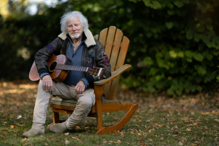 Le chanteur Hugues Aufray, 96 ans, joue de la guitare dans le jardin de sa maison à Marly-le-Roi, dans les Yvelines, le 14 octobre 2025 ( AFP / JOEL SAGET )