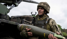 Un militaire ukrainien porte un obus pour un obusier automoteur Caesar avant de tirer en direction des troupes russes près d'Avdiivka