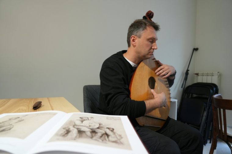 Oleksandr Savtchouk egrène les arpèges sur sa bandoura, à Kharkiv le 18 octobre 2025 ( AFP / OLEKSII FILIPPOV )