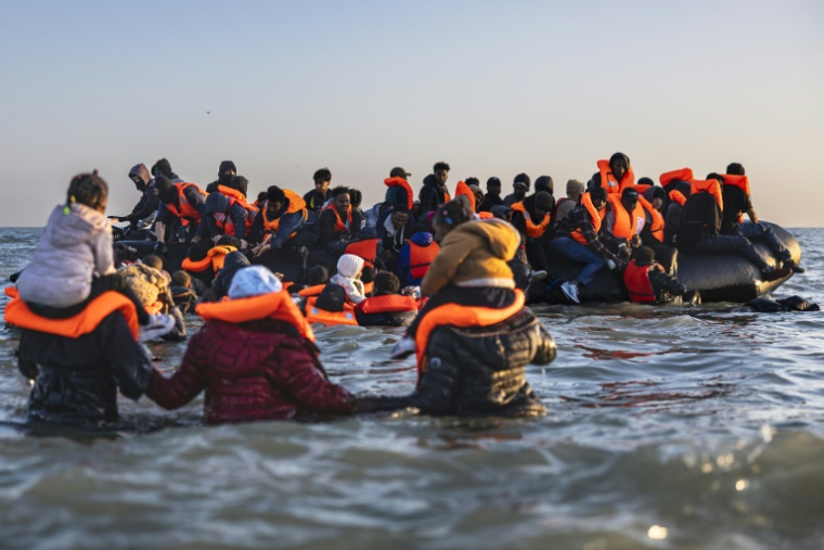 Des migrants avancent dans l'eau pour embarquer sur le bateau d'un passeur et tenter de traverser la Manche au large de la plage de Gravelines, le 16 juin 2025 dans le Nord ( AFP / Sameer Al-DOUMY )