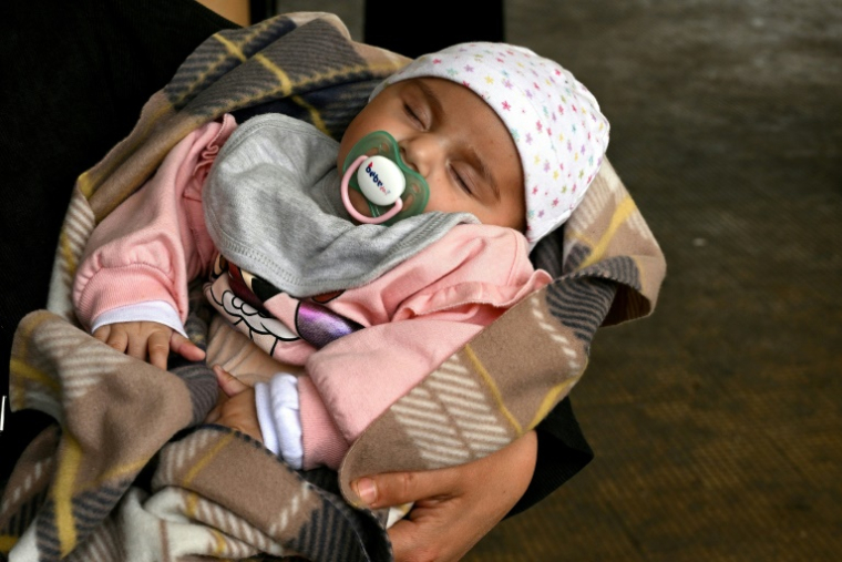 Une femme tient son bébé dans un couloir d’une école transformée en centre d’accueil pour personnes déplacées, dans la région de Dekwaneh, à l’est de Beyrouth, le 15 avril 2026 ( AFP / Joseph EID )