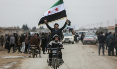 Des hommes à moto brandissent un drapeau syrien alors que les forces gouvernementales entrent dans le bastion kurde de Qamichli, le 3 février 2026 ( AFP / Bakr ALKASEM )
