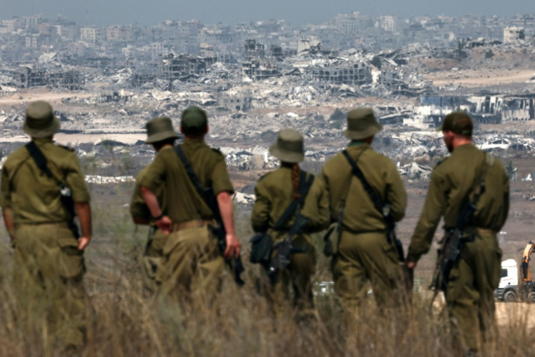 Des soldats de l'armée israélienne observent des bâtiments détruits dans la bande de Gaza depuis la frontière avec le territoire palestinien, le 13 août 2025 ( AFP / Jack GUEZ )