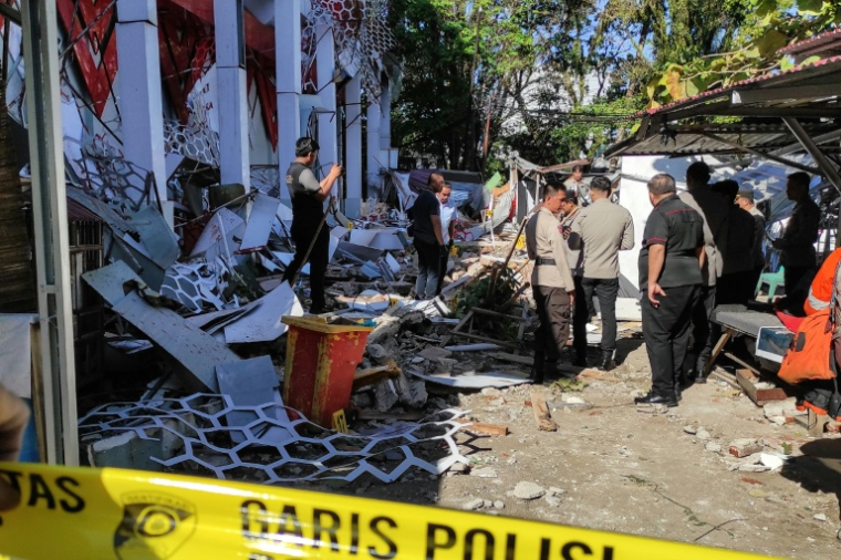 Des policiers inspectent un bâtiment touché par un séisme, le 2 avril 2026 à Manado en Indonésie ( AFP / Tonny Rarung )