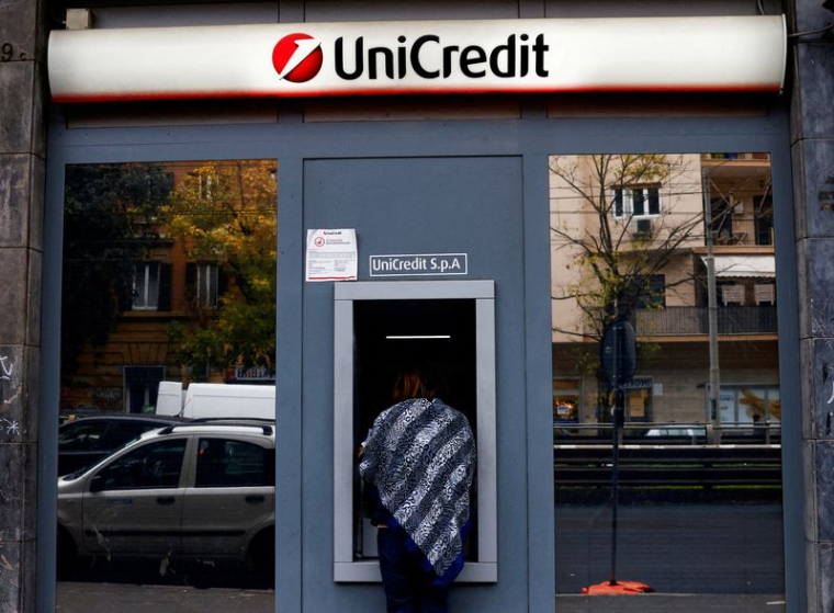 Une personne utilise un distributeur automatique de billets dans une succursale de la banque UniCredit à Rome, en Italie