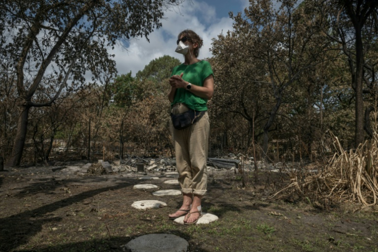 Une habitante mesure l'étendue des dégâts causés par l'incendie qui a ravagé la commune de Le Porge, en Gironde, le 31 juillet 2026  ( AFP / Ed JONES )