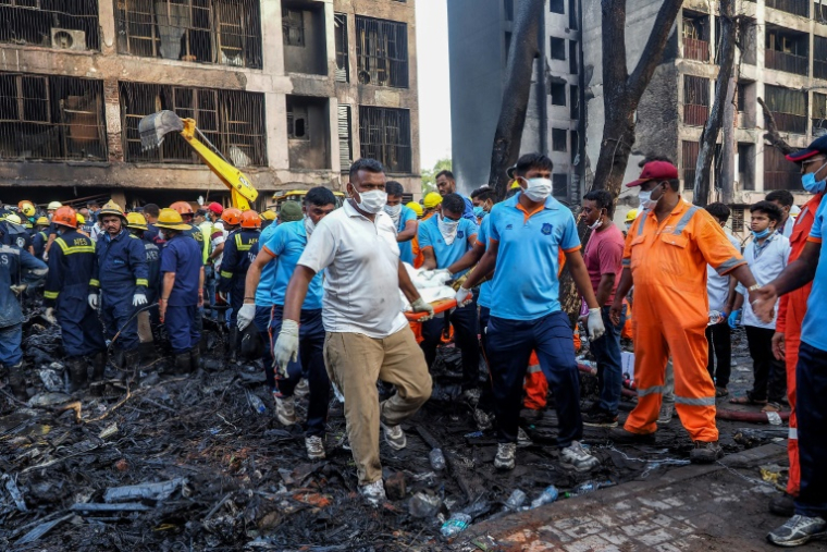Des sauveteurs transportent le corps d'une victime sur le site où un avion d'Air India s'est écrasé, dans un quartier résidentiel d'Ahmedabad, le 12 juin 2025 en Inde ( AFP / Sam PANTHAKY )