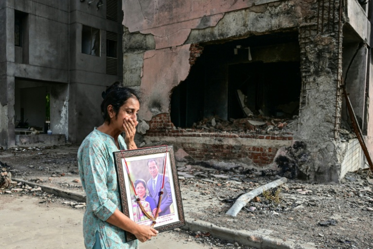 Une femme tenant un portrait de ses proches, décédés dans le crash du vol Air India 171 l'année dernière, fond en larmes lors d'une visite sur le site de l'accident à Ahmedabad, le 11 juin 2026.  ( AFP / Shammi MEHRA )