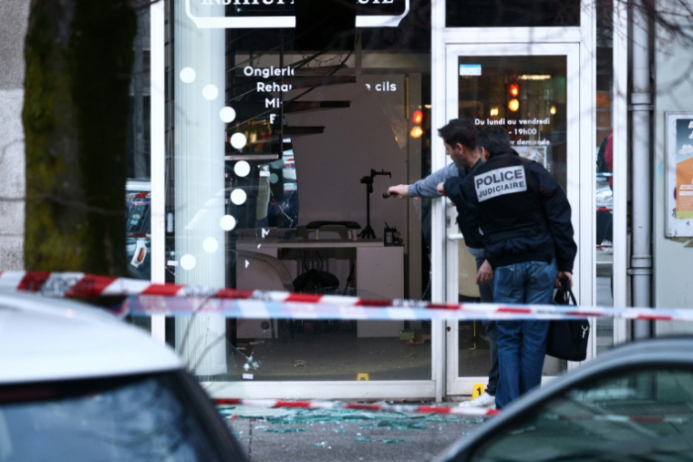 Des policiers examinent la vitrine d'un salon de beauté contre lequel une grenade a été lancée à Grenoble, le 6 février 2026 en Isère ( AFP / Alex MARTIN )