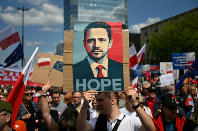 Un homme brandit un portrait du candidat pro-UE et maire de Varsovie Rafal Trzaskowski, le 25 mai 2025 à Varsovie ( AFP / Sergei GAPON )