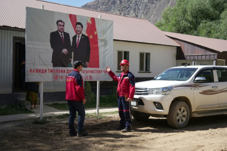 Des employés de l'entreprise Talco Gold, devant une affiche du président chinois Xi Jinping (d) et du président tadjik Emomali Rakhmon à la mine d'antimoine de Saritag, dans l'ouest du Tadjikistan, le 26 août 2025 ( AFP / STRINGER )