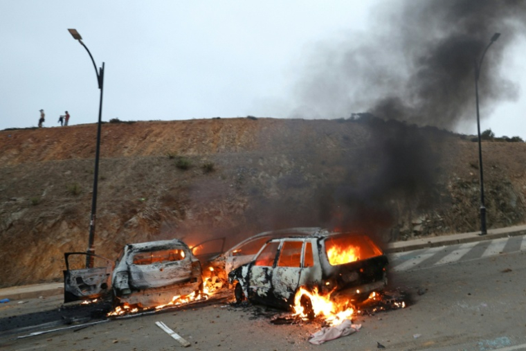 Des voitures brûlent à la suite d'affrontements près de la ville marocaine de Fnideq, située à la frontière avec l'enclave espagnole Ceuta, le 31 juillet 2026 ( AFP / Abdel Majid BZIOUAT )