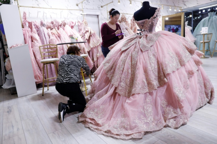Ariella Santoyo (c), propriétaire de la boutique "My Quince World" dans le quartier Little Village de Chicago, prépare une robe pour une cliente, le 10 octobre 2025 dans l'Illinois ( AFP / OCTAVIO JONES )