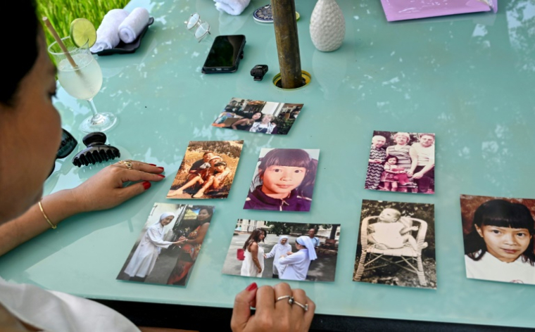 Odile Dussart, évacuée de Saïgon alors qu'elle n'était qu'un bébé de 11 mois, quelques semaines avant la fin de la guerre du Vietnam il y a 50 ans, montre des photos de famille dans sa nouvelle maison à Hoi An, le 12 avril 2025 ( AFP / Nhac NGUYEN )