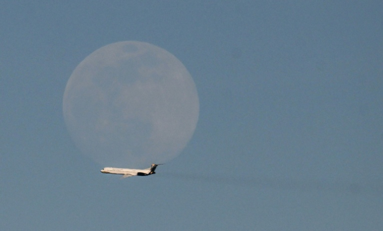 Un avion de la compagnie vénézuélienne Rutaca passe devant la lune, vu depuis l'aéroport international Simon Bolivar à Maiquetia, Venezuela, le 3 décembre 2025 ( AFP / Juan BARRETO )