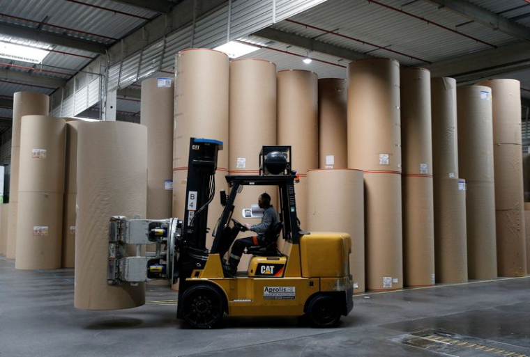 Un employé transporte une bobine de papier géante