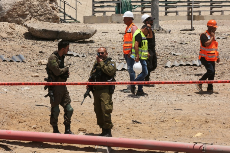 Des membres des forces de sécurité israéliennes sur un site frappé par un tir iranien à Ashdod, dans le sud d'Israël, le 23 juin 2025 ( AFP / GIL COHEN-MAGEN )