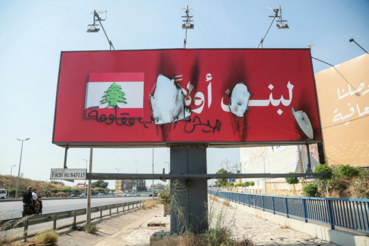 Une affiche "Le Liban d'abord" vandalisée par les mots "Armée, Peuple, Résistance" et incendiée, le long de la route de l'aéroport de Beyrouth, le 28 juin 2026 au Liban, après l'accord-cadre conclu entre le Liban et Israël ( AFP / ibrahim AMRO )