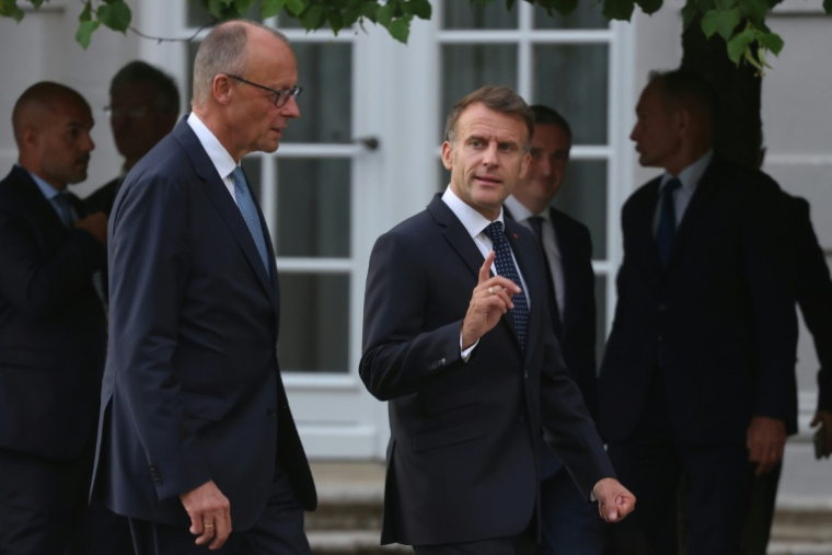 Le chancelier allemand Friedrich Merz (g) et le président français Emmanuel Macron marchent côte à côte après s’être adressés aux journalistes avant leur rencontre au château de Bensberg dans l’ouest de l’Allemagne, le 16 juillet 2026, à la veille du conseil des ministres franco-allemand. ( AFP / Ludovic MARIN )
