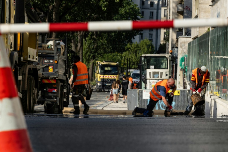 Des ouvriers étendent de l'asphalte sur une rue de Paris, le 22 juin 2026 lors d'un épisode de canicule en France ( AFP / Joel Saget )