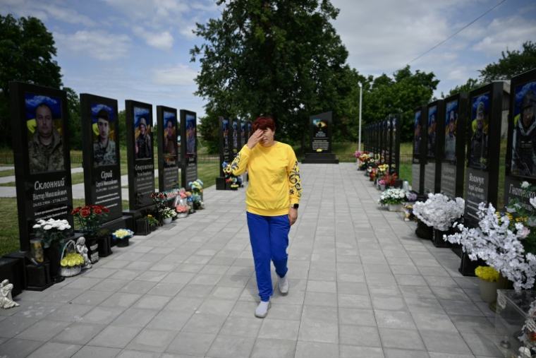 Nadia, 57 ans, mère du soldat ukrainien tué Andriï Doubnytsky, essuie ses larmes au milieu d'une allée du village de Stepantsi, dans la région de Tcherkassy, le 7 juillet 2026. ( AFP / Genya SAVILOV )
