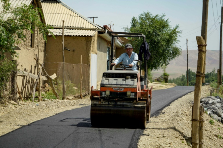 Un ouvrier asphalte une route dans le village de Mehrobod, un projet de développement financé par des migrants tadjiks à l'étranger, le 25 mai 2025 au Tadjikistan ( AFP / STRINGER )