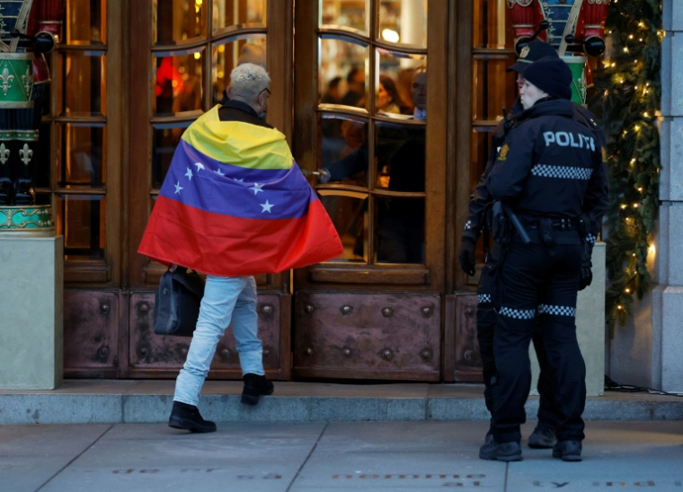 Un homme enveloppé d'un drapeau vénézuelien rentre dans le Grand Hotel d'Oslo, le 9 decembre 2025 ( AFP / Odd ANDERSEN )