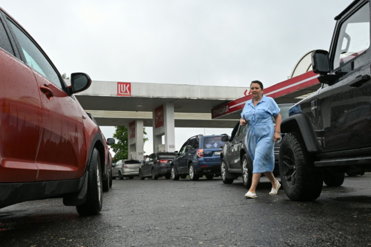 Une femme marche au milieu d'une file de véhicules dans une station-service à Vologda, en Russie, le 14 juillet 2026 ( AFP / Igor IVANKO )