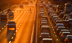 Un piéton traverse un passage clouté à côté des voitures dans la circulation sur une route principale au coucher du soleil à Pékin