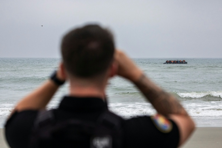 Un gendarme observe des migrants qui tentent la traversée de la Manche à Neufchatel-Hardelot, le 13 août 2025 ( AFP / Sameer Al-DOUMY )