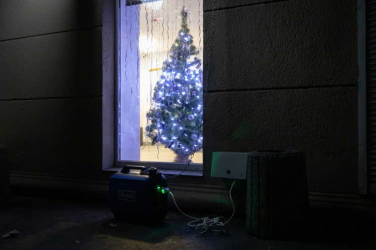 Un groupe électrogène à l'extérieur d'une maison où un sapin de Noël est illuminé, lors d'une coupure de courant à Odessa, après des frappes de missiles et de drones russes contre des infrastructures énergétiques ukrainiennes, le 22 décembre 2025 ( AFP / Oleksandr GIMANOV )
