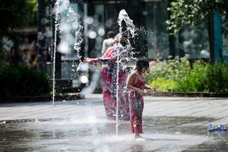 Une enfant se rafraîchit sous un jet d'eau dans un parc à Bruxelles, le 19 juin 2026 ( AFP / Nicolas TUCAT )