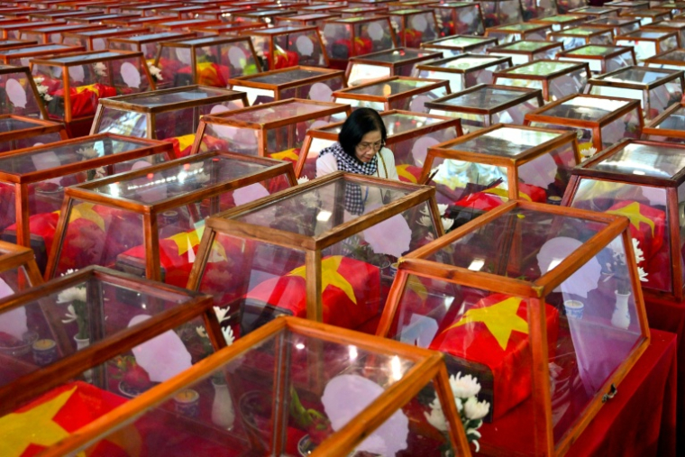 Une femme au milieu de cercueils contenant les dépouilles de soldats tombés au combat, au parc Le Thi Rieng à Hô Chi Minh-Ville, le 14 octobre 2026 au Vietnam ( AFP / Nhac NGUYEN )