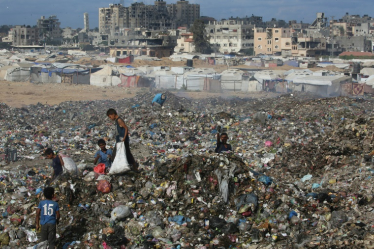 Des enfants palestiniens cherchent des objets à sauver dans un tas d'ordures près de destructions dans le camp de réfugiés de Bureij, dans le centre de la bande de Gaza, le 6 octobre 2025 ( AFP / Eyad BABA )