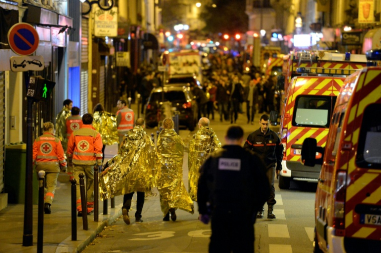 Des membres de la Croix-Rouge, des policiers et pompiers rue Oberkampf, près de la salle de concert du Bataclan à Paris, lors des attaques du 13 novembre 2025 ( AFP / Miguel MEDINA )