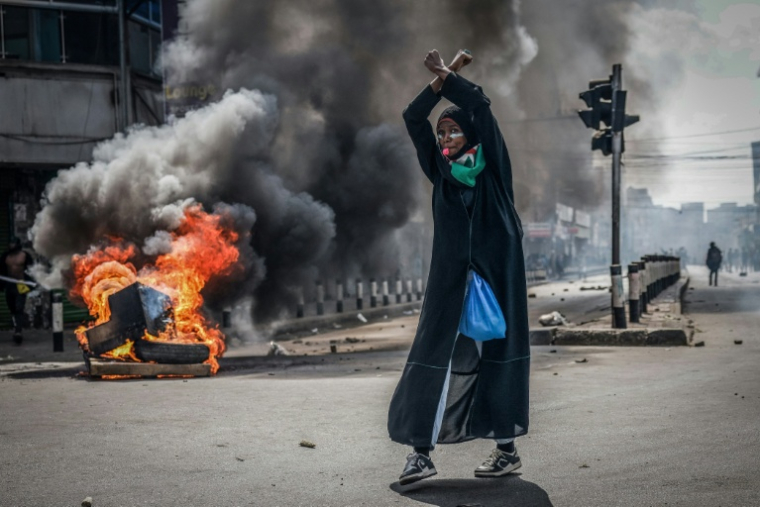 Une manifestante devant une barricade en feu le 25 juin 2025 dans le centre-ville de Nairobi ( AFP / Luis TATO )