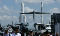 Un avion militaire Airbus A400M Grizzly et des fusées spatiales Ariane 1 (d) et Ariane 5 exposés au Salon du Bourget, le 16 juin 2025 près de Paris ( AFP / Alain JOCARD )