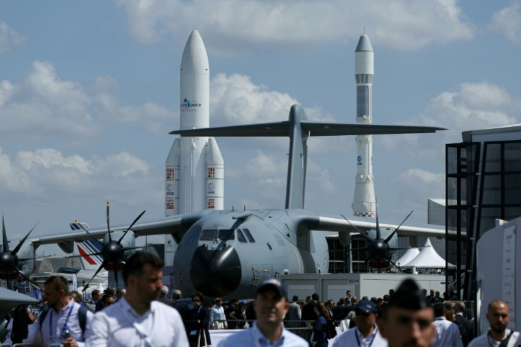 Un avion militaire Airbus A400M Grizzly et des fusées spatiales Ariane 1 (d) et Ariane 5 exposés au Salon du Bourget, le 16 juin 2025 près de Paris ( AFP / Alain JOCARD )