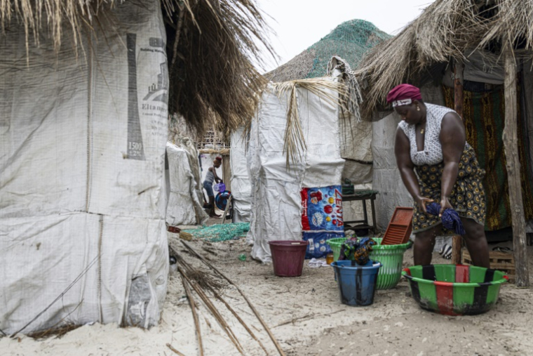 Une habitante devant sa cabane menacée par la montée des eaux sur l'île de Nyangai, au large de la Sierra Leone, le 29 avril 2025 ( AFP / PATRICK MEINHARDT )