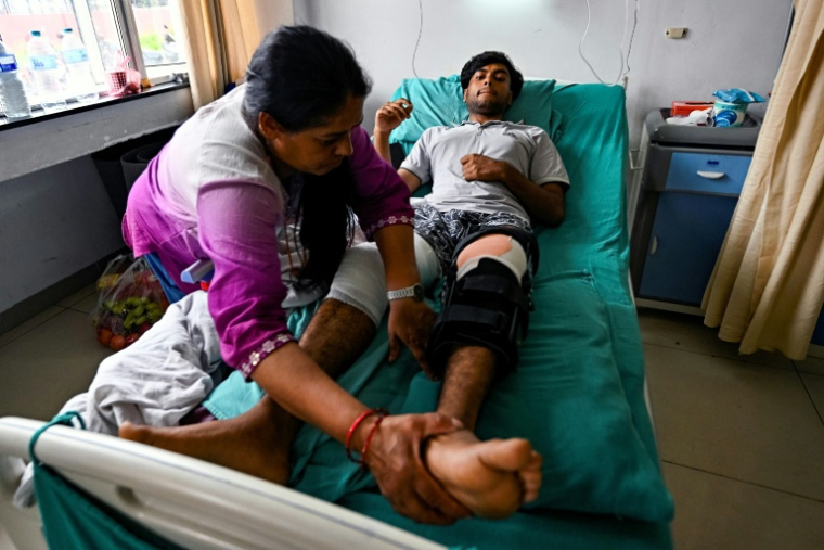 Subash Dhakal, un manifestant de 19 ans grièvement blessé aux genoux, avec sa mère, Bhawani Dhakal, à l'hôpital public de Katmandou, le 14 septembre 2025 ( AFP / Pedro PARDO )