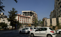 Des automobilistes passent devant un bâtiment endommagé après qu’il a été visé par une frappe israélienne dans la capitale iranienne, Téhéran, le 13 juin 2025 ( AFP / ATTA KENARE )